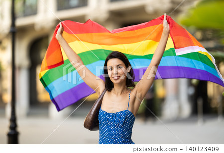 Young woman with LGBT flag on city street Young woman with LGBT flag on city street 140123409