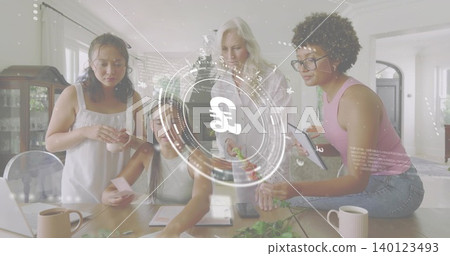 Working women wearing sleeveless tops arranging greenery on wood table in kitchen, laptop pound HUD 140123493