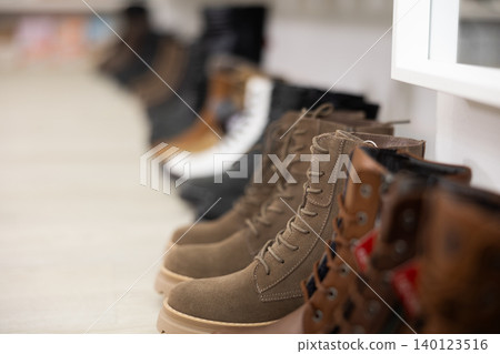On wooden white shelve of store there are various items of women shoes boots On wooden white shelve of store there are various items of women shoes boots 140123516