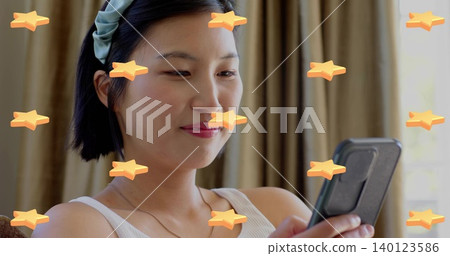 Holding phone, Korean woman viewing screen on sofa in tank top headband necklace with star stickers Holding phone, Korean woman viewing screen on sofa in tank top headband necklace with star stickers 140123586