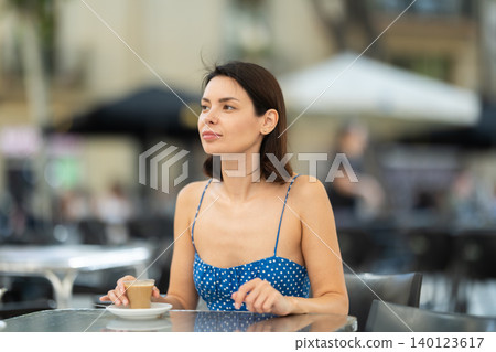 Smiling stylish brunette woman drinking espresso coffee while sitting on terrace of street cafe 140123617