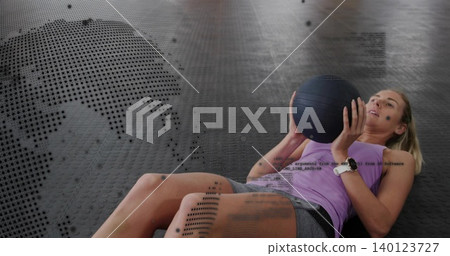 Holding black med ball, woman working core on gym rubber floor, purple top, smartwatch, copy space 140123727