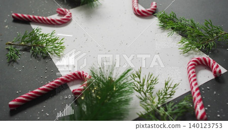 Lying white paper sheet on dark gray tabletop, framed by candy canes, pine sprigs, snow, overlays Lying white paper sheet on dark gray tabletop, framed by candy canes, pine sprigs, snow, overlays 140123753