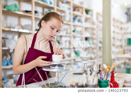 Teenage girl makes ceramic cup in ceramic workshop Teenage girl makes ceramic cup in ceramic workshop 140123793