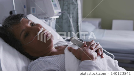 Resting senior woman lying in hospital bed, in striped top with nasal cannula and pulse oximeter Resting senior woman lying in hospital bed, in striped top with nasal cannula and pulse oximeter 140123841