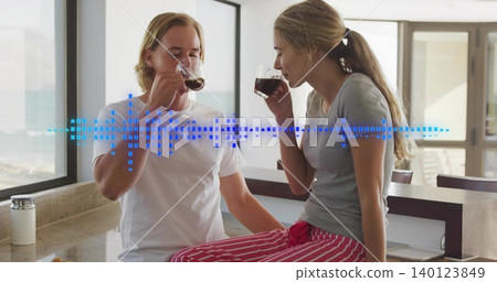 Sipping couple holding clear mugs in home kitchen, woman in striped PJs, with waveform overlay Sipping couple holding clear mugs in home kitchen, woman in striped PJs, with waveform overlay 140123849