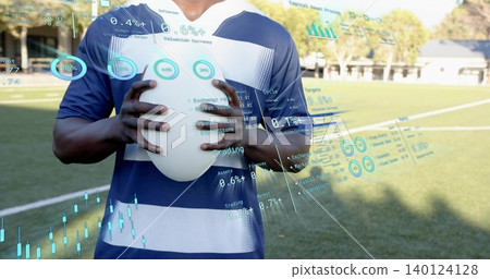 Holding player in blue jersey on lined sports field, displaying holograms and white oval ball Holding player in blue jersey on lined sports field, displaying holograms and white oval ball 140124128