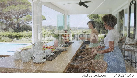 Arranging dishes, two women placing teacups on long counter on covered patio with teapot and fruit Arranging dishes, two women placing teacups on long counter on covered patio with teapot and fruit 140124149