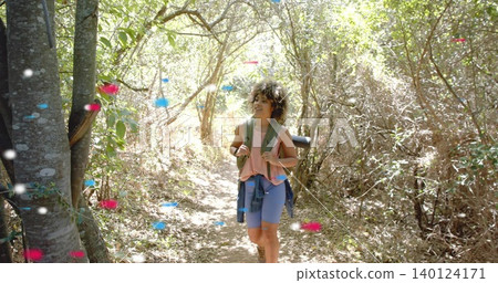 Walking woman pink shorts with green-pack mat jacket-tied waist on woods trail with color specks Walking woman pink shorts with green-pack mat jacket-tied waist on woods trail with color specks 140124171