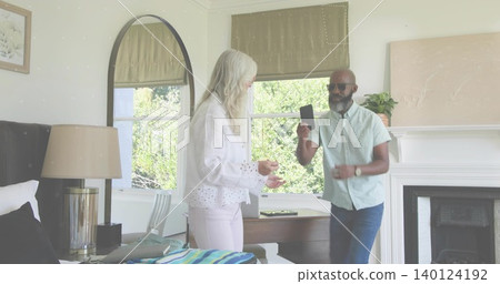 Holding smartphone, senior woman in eyelet blouse and man in light shirt checking screen at home Holding smartphone, senior woman in eyelet blouse and man in light shirt checking screen at home 140124192