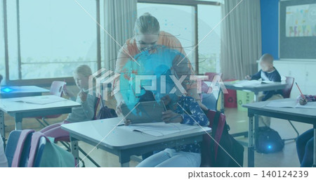 Leaning teacher in orange top and glasses assisting pupil at school desk with tablet hologram 140124239