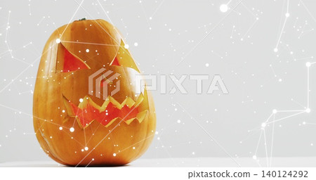 Sitting carved pumpkin glowing with orange-red light on white tabletop, network overlay, copy space Sitting carved pumpkin glowing with orange-red light on white tabletop, network overlay, copy space 140124292