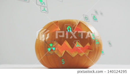 Sitting carved pumpkin glowing with internal light on tabletop, projecting green holographic icons Sitting carved pumpkin glowing with internal light on tabletop, projecting green holographic icons 140124295