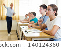 Teenage students studying in classroom with teacher, writing lectures 140124360
