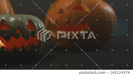 Glowing two carved jack-o'-lanterns casting orange reflections on studio tabletop, calibration grid Glowing two carved jack-o'-lanterns casting orange reflections on studio tabletop, calibration grid 140124374