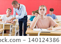 Young students sitting at desks in classroom 140124386