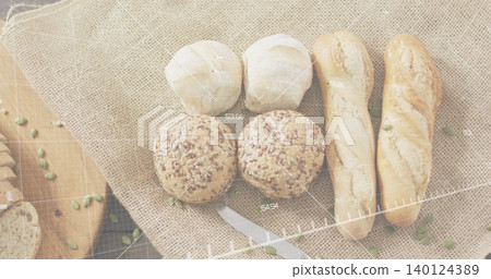 Displaying seeded rolls and baguettes sitting on burlap at dark wooden table, with serrated knife Displaying seeded rolls and baguettes sitting on burlap at dark wooden table, with serrated knife 140124389