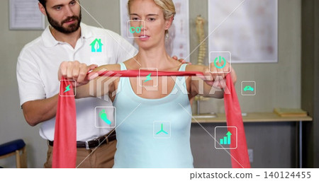 Stretching woman in light blue tank top pulling red resistance band in rehab clinic, spine model Stretching woman in light blue tank top pulling red resistance band in rehab clinic, spine model 140124455