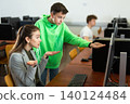 Tween schoolboy helping young puzzled woman working with computer 140124484