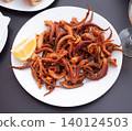 Fried tentacles squid served on white plate with potatoes, lemon slices 140124503