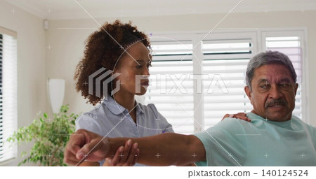 Guiding caregiver supporting senior extending right arm at home, green and blue shirts, shutters Guiding caregiver supporting senior extending right arm at home, green and blue shirts, shutters 140124524