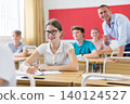 High school student teenage girl studying in college with classmates, making notes of teacher lecture 140124527