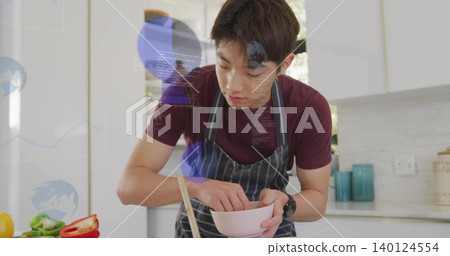 Mixing Korean teen in maroon tee and apron preparing vegetables at modern kitchen, with pink bowl Mixing Korean teen in maroon tee and apron preparing vegetables at modern kitchen, with pink bowl 140124554