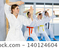 Young female students repeat position and perform sequence of punches and painful techniques kata 140124604