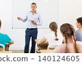 Teacher explaining studying material to teenagers during lesson 140124605
