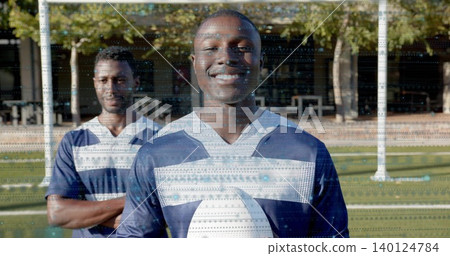 Smiling male athlete holding white football on grassy field, wearing navy and white jerseys Smiling male athlete holding white football on grassy field, wearing navy and white jerseys 140124784