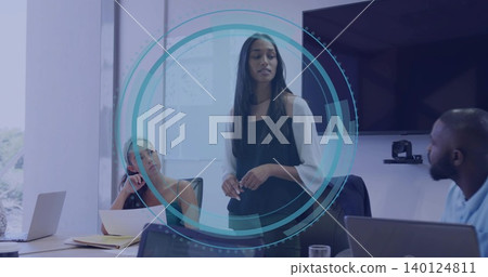 Presenting woman in black dress speaking with team in meeting room with laptops and display Presenting woman in black dress speaking with team in meeting room with laptops and display 140124811