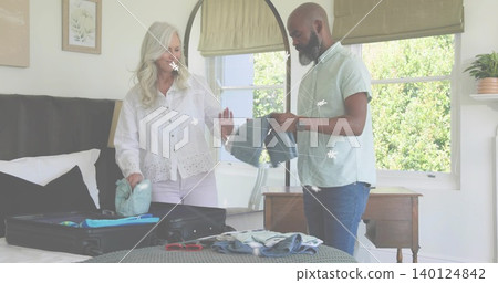 Packing woman in eyelet blouse and man in light shirt folding clothes in bedroom, with suitcase Packing woman in eyelet blouse and man in light shirt folding clothes in bedroom, with suitcase 140124842