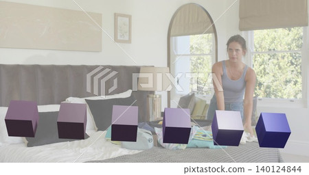 Leaning woman in tank top, jeans, arranging suitcase on bed in bedroom, purple cubes, copy space Leaning woman in tank top, jeans, arranging suitcase on bed in bedroom, purple cubes, copy space 140124844