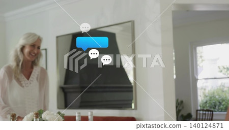 Smiling senior woman wearing white-blouse standing left of table, mirror, chat bubbles, copy space Smiling senior woman wearing white-blouse standing left of table, mirror, chat bubbles, copy space 140124871