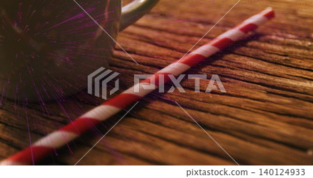 Lying red white striped paper straw crossing weathered wood, showing ceramic mug and purple flare Lying red white striped paper straw crossing weathered wood, showing ceramic mug and purple flare 140124933