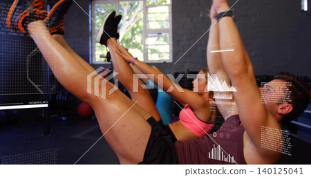 Performing pair in tanktop and pink sports bra doing V-ups in gym on mats, HUD overlays Performing pair in tanktop and pink sports bra doing V-ups in gym on mats, HUD overlays 140125041