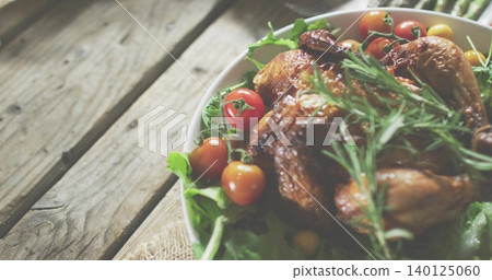 Showing roasted chicken in white bowl on rustic table with greens rosemary cherry tomatoes on vine Showing roasted chicken in white bowl on rustic table with greens rosemary cherry tomatoes on vine 140125060
