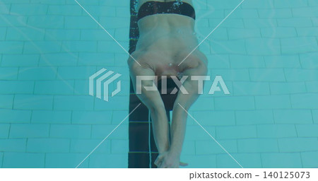 Gliding male swimmer in dark swim cap and trunks cutting through tiled pool lane stripe, bubbles Gliding male swimmer in dark swim cap and trunks cutting through tiled pool lane stripe, bubbles 140125073