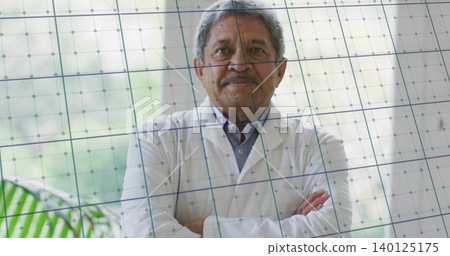 Standing senior man wearing white lab coat, crossing arms, facing camera at clinic, grid glass Standing senior man wearing white lab coat, crossing arms, facing camera at clinic, grid glass 140125175