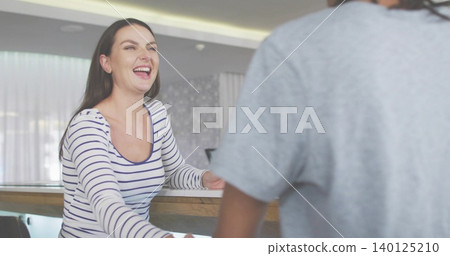 Laughing mid adult woman reaching behind wooden counter, wearing striped shirt, monitor visible Laughing mid adult woman reaching behind wooden counter, wearing striped shirt, monitor visible 140125210