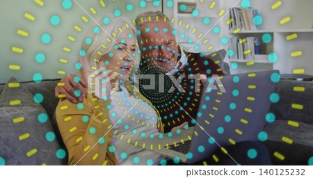 Leaning couple in dark sweater, yellow cardigan, viewing laptop on sofa at home with teal overlay Leaning couple in dark sweater, yellow cardigan, viewing laptop on sofa at home with teal overlay 140125232