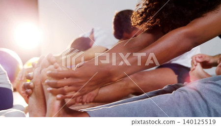 Reaching curly woman stretching on gym mats with ball, sportswear, bare toes, light flare Reaching curly woman stretching on gym mats with ball, sportswear, bare toes, light flare 140125519