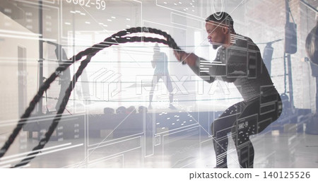 Swinging man in dark athletic gear using battle ropes at gym with kettlebells, HUD, copy space Swinging man in dark athletic gear using battle ropes at gym with kettlebells, HUD, copy space 140125526