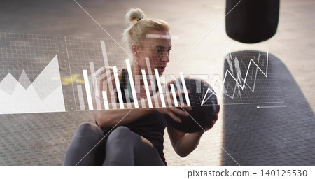 Woman wearing athletic wear performing seated core at gym, holding medicine ball with HUD overlays Woman wearing athletic wear performing seated core at gym, holding medicine ball with HUD overlays 140125530