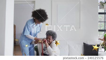 Leaning nurse in blue scrubs steadying senior in living room with red cane, stethoscope, gold stars Leaning nurse in blue scrubs steadying senior in living room with red cane, stethoscope, gold stars 140125576