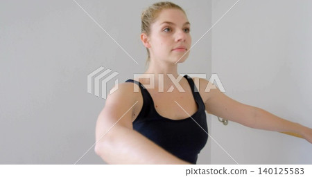 Standing woman wearing black tank raising arms shoulder-height in studio, with bracket and rail Standing woman wearing black tank raising arms shoulder-height in studio, with bracket and rail 140125583