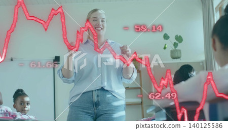 Female teacher speaking and gesturing in classroom in light-blue top and jeans, red graph overlay Female teacher speaking and gesturing in classroom in light-blue top and jeans, red graph overlay 140125586