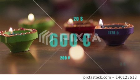 Flickering painted diyas showing flames on polished wood table, circular bokeh, turquoise overlays Flickering painted diyas showing flames on polished wood table, circular bokeh, turquoise overlays 140125618
