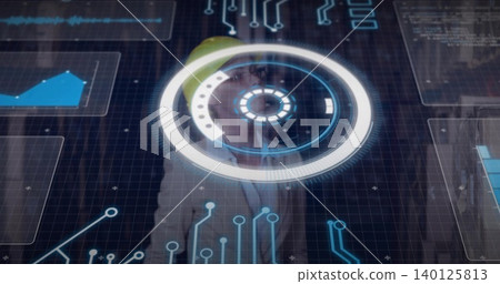 Standing engineer with yellow hard hat and blazer using circular HUD and graphs in control room Standing engineer with yellow hard hat and blazer using circular HUD and graphs in control room 140125813