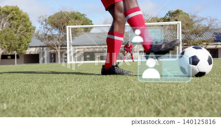Kicking soccer player aiming and striking ball on school pitch, showing goal, red kit, AR overlays Kicking soccer player aiming and striking ball on school pitch, showing goal, red kit, AR overlays 140125816